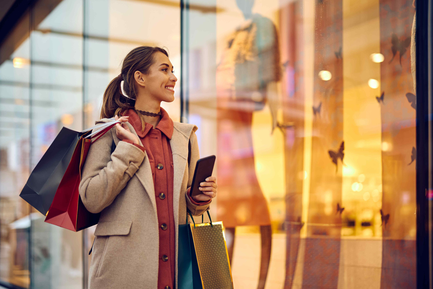 Happy woman with shopping bags looking at store windows while walking through city