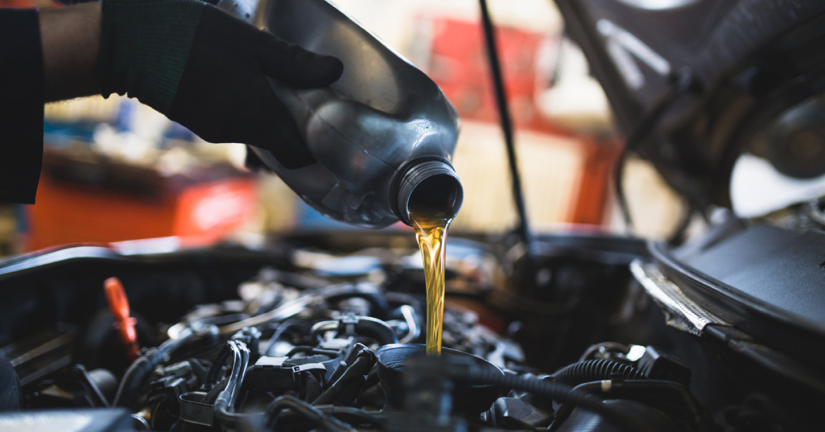 a mechanic pouring new engine oil to a car