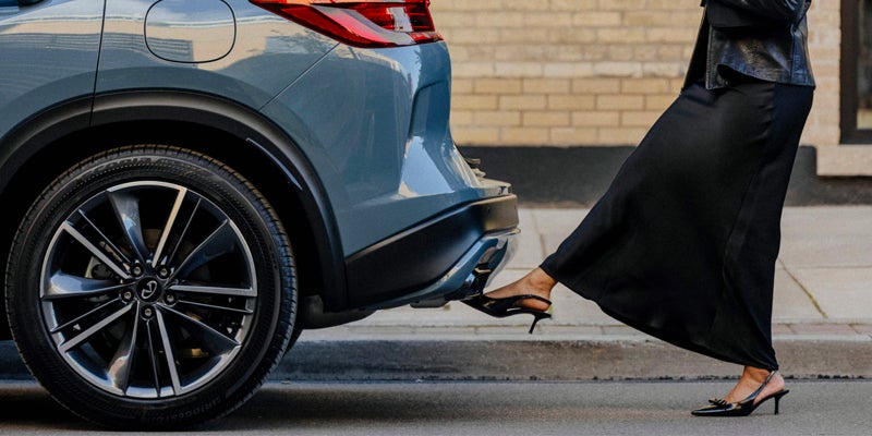 Person using a foot-activated sensor to open a car's power liftgate.