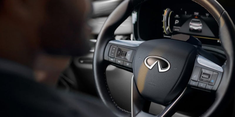 Close-up of an Infiniti steering wheel with a digital dashboard behind it