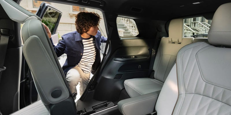 Young man entering the rear seating area of an Infiniti QX80