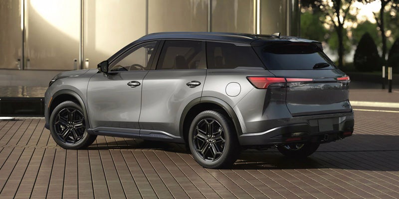 A sleek grey Infiniti SUV parked on a wooden deck at dusk