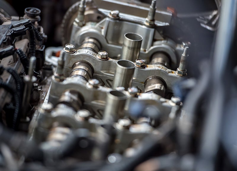 Close-up of a car engine’s cylinder head with various metal components and fasteners.