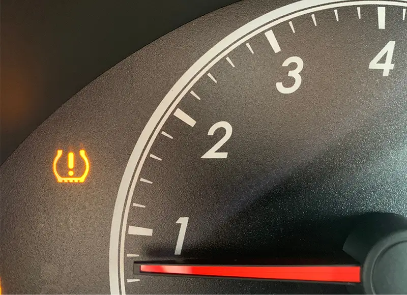 A car's tire pressure monitoring system light illuminates, indicating low tire pressure.